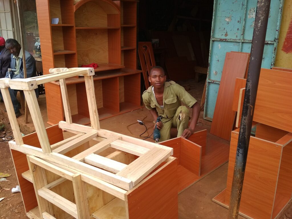 A young Nigerian carpenter building furniture outside a local workshop