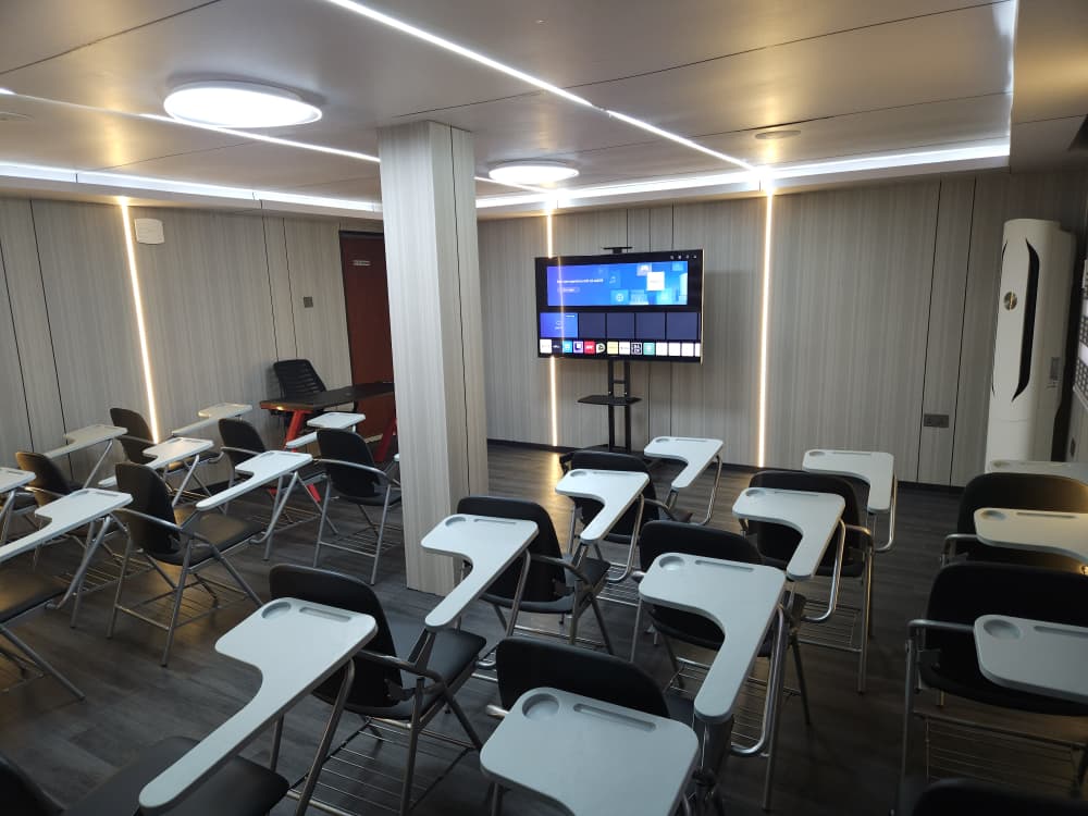 The Castle Academy training room in Ikeja, set out with desk chairs facing a smart TV